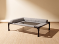 Breeze Cot in grey woven fabric — studio view on oak floor